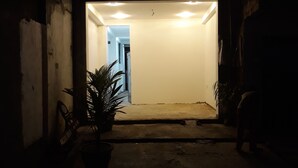 A dimly lit entrance with a concrete floor, a potted plant, and a chair. - Arcade Beach Hotel (Induruwa)