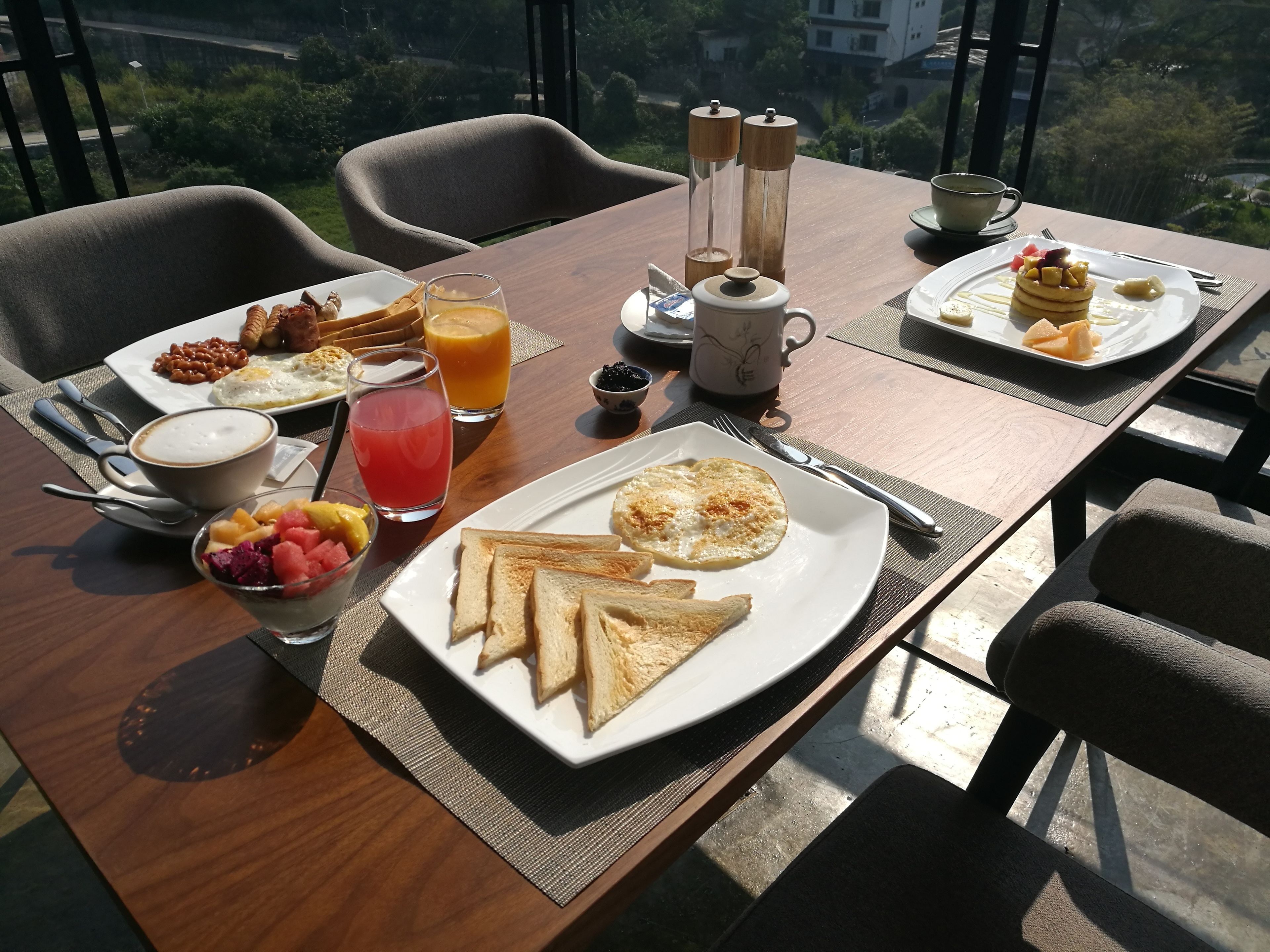 A breakfast setting with a table, chairs, and a view of greenery.