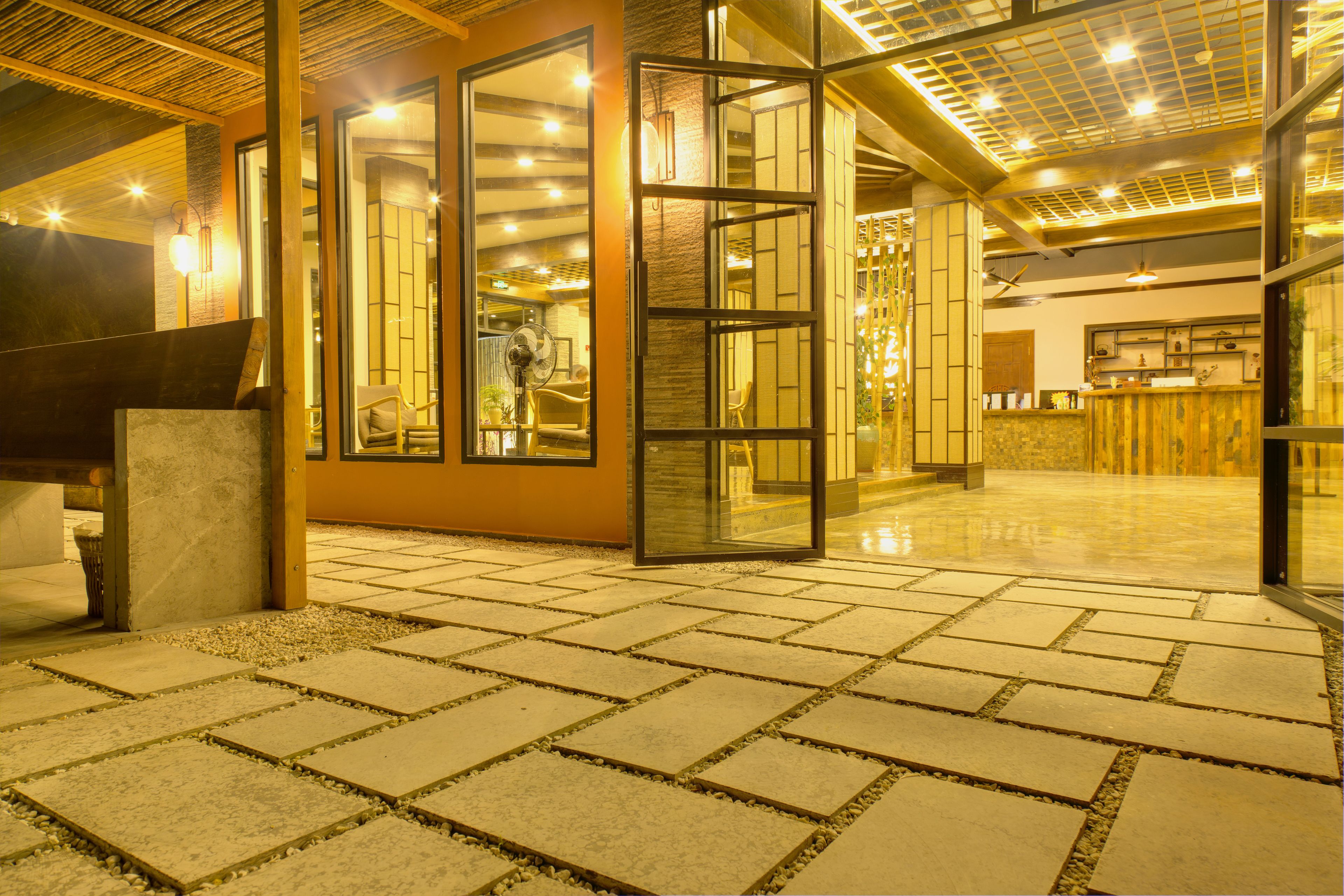 A spacious lobby with a tiled floor, a reception desk, and a large open door leading to another area.
