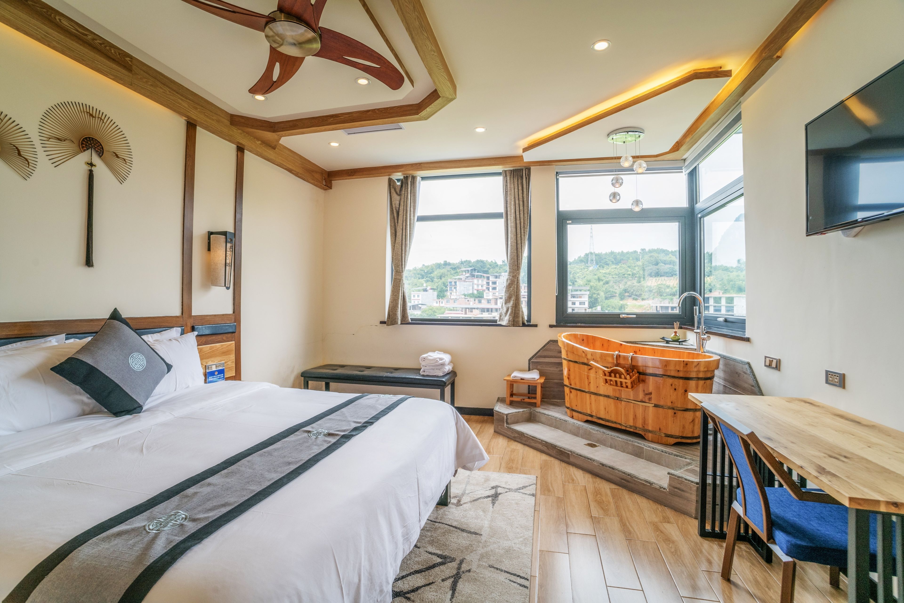 Una camera d'albergo con un letto, una scrivania in legno, una vasca da bagno e un televisore.