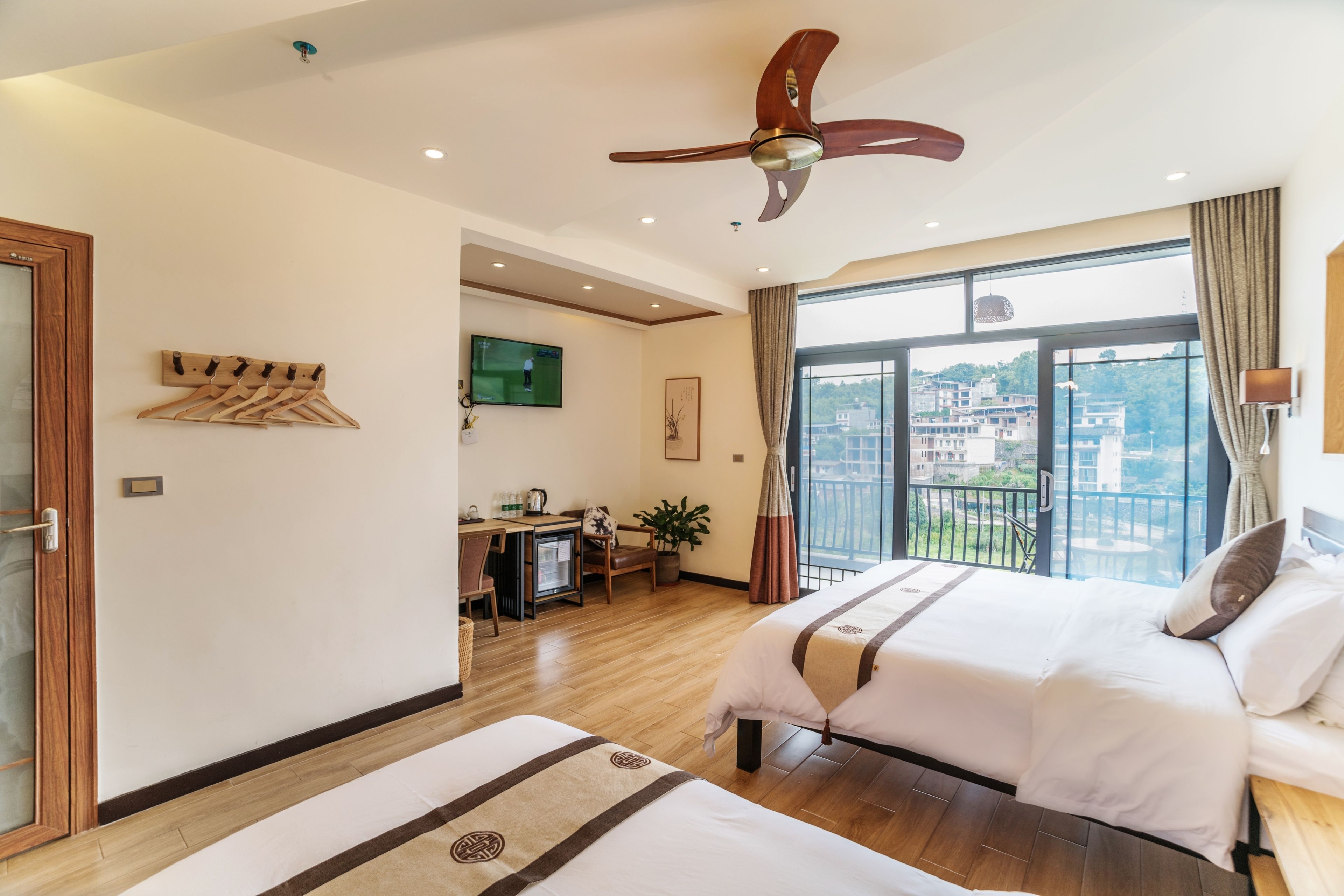 Une chambre d’hôtel avec un grand lit, un bureau, une télévision et un balcon offrant une vue sur la ville.