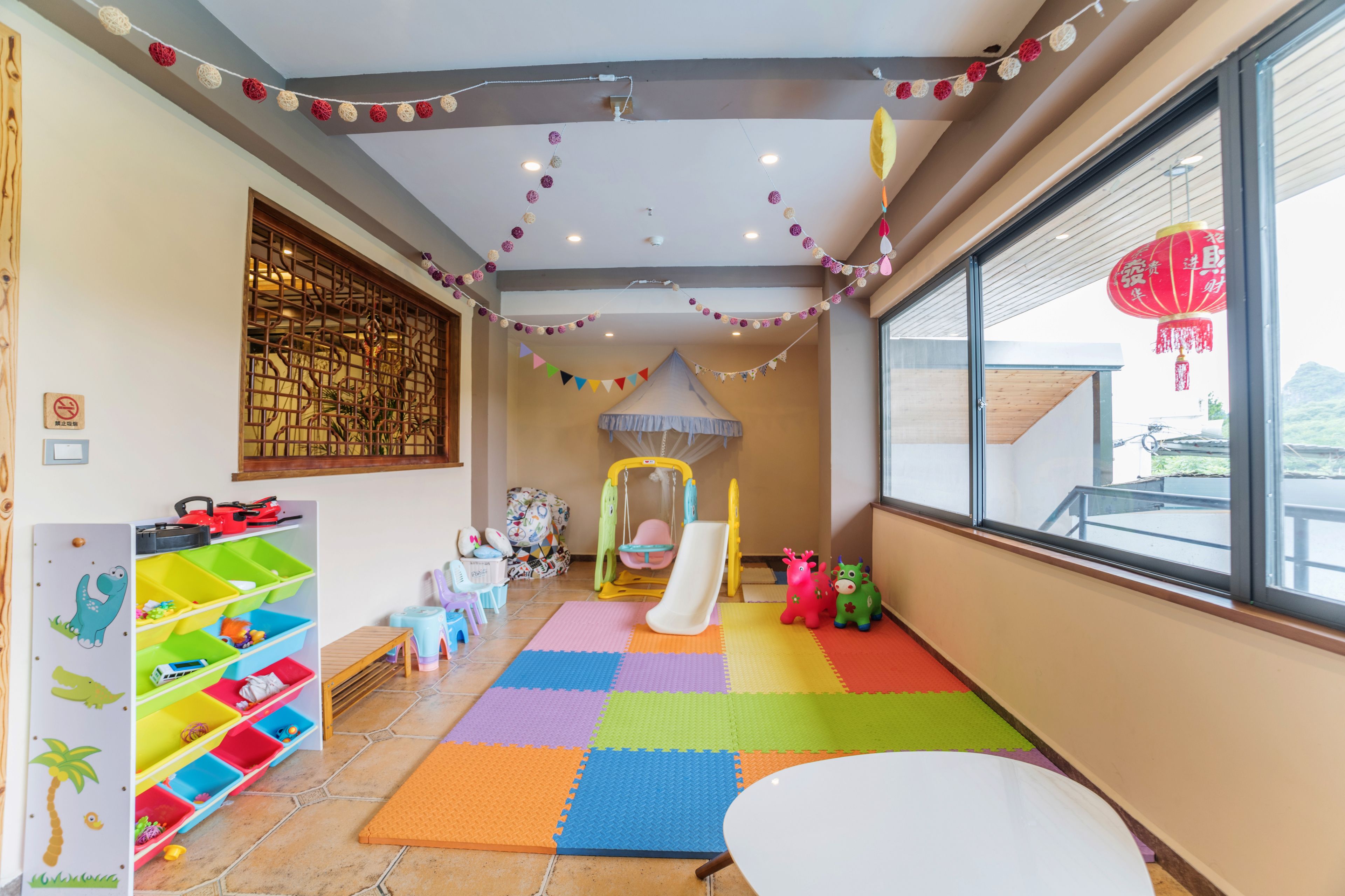 A children's playroom with a colorful play mat, a slide, and storage units.