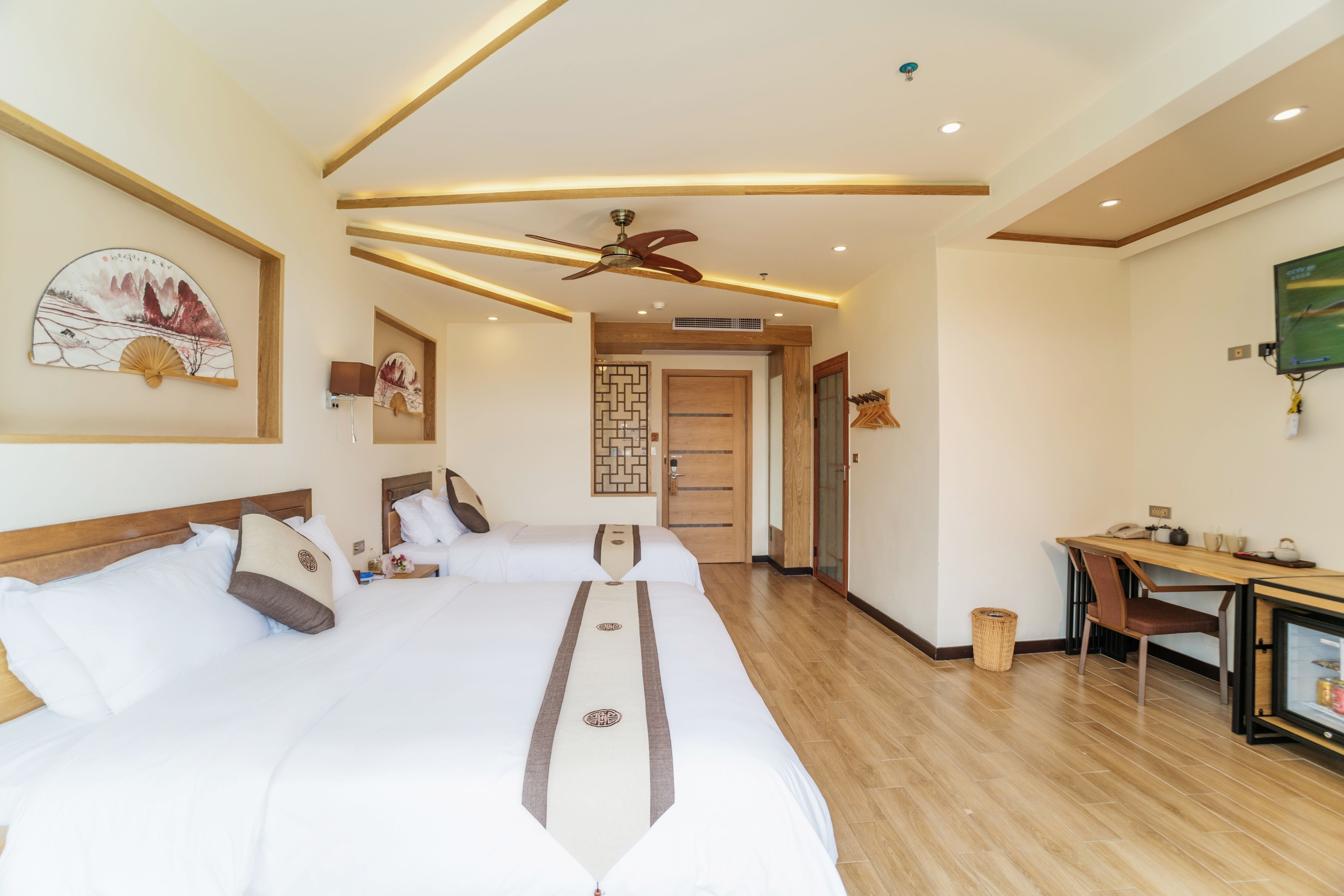 A hotel room with a large bed, a desk, and a ceiling fan.