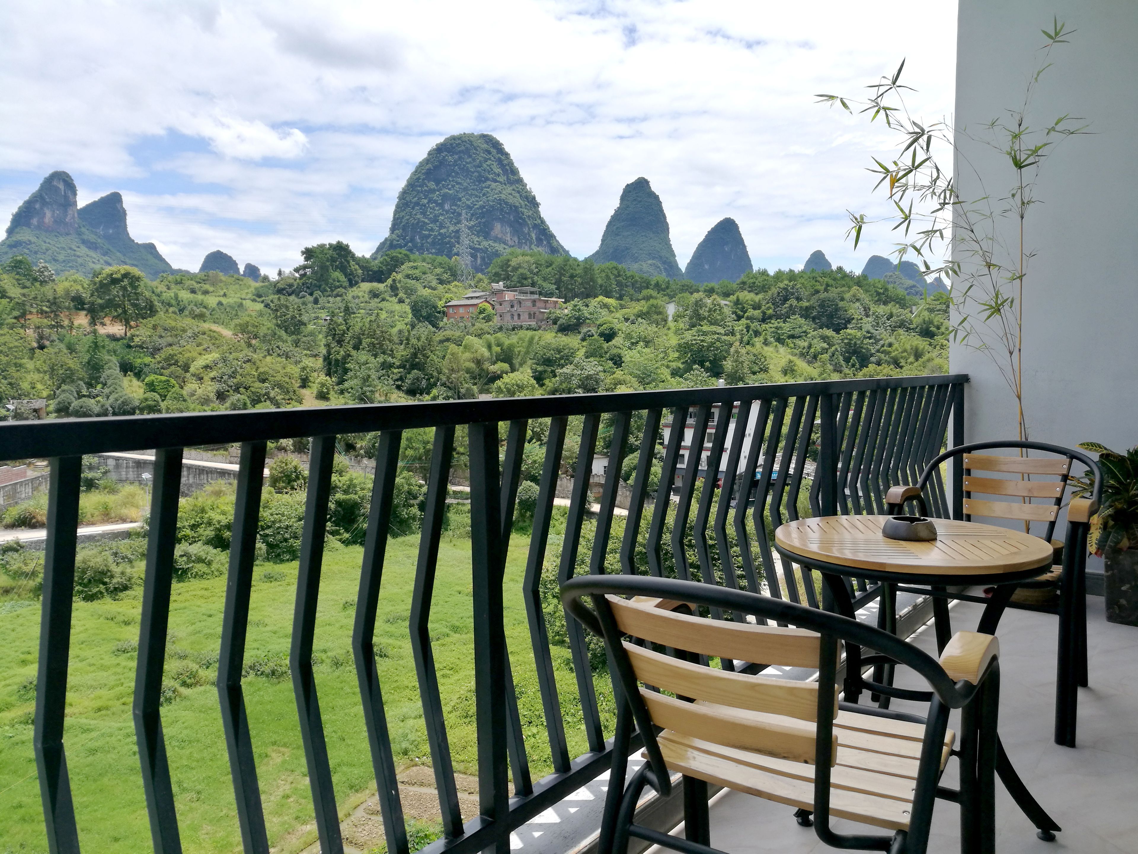 Un balcón con vistas a verdes colinas y una cordillera de montañas.