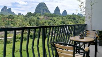 A balcony with a view of green hills and a mountain range.