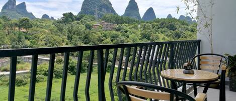 Un balcón con vistas a verdes colinas y una cordillera de montañas.