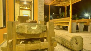 A wooden bench with a stone basin in the center, surrounded by a stone wall and a wooden pergola.