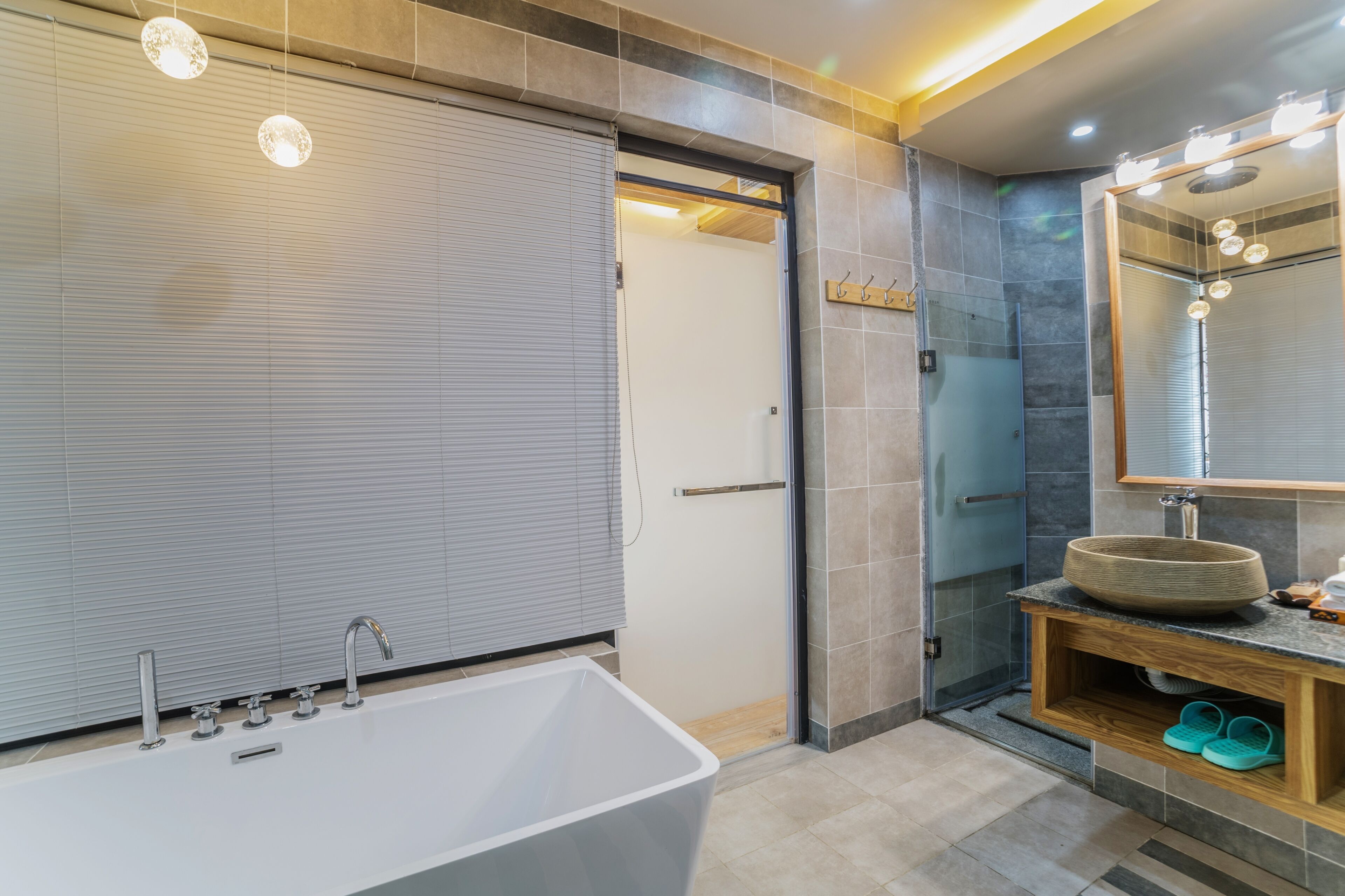A modern bathroom with a large bathtub, a vanity with a round sink, and a mirror with lights.