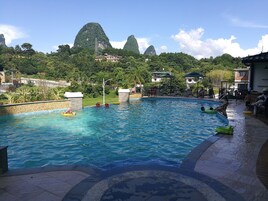 Una piscina al aire libre, sombrillas, sillones reclinables de piscina