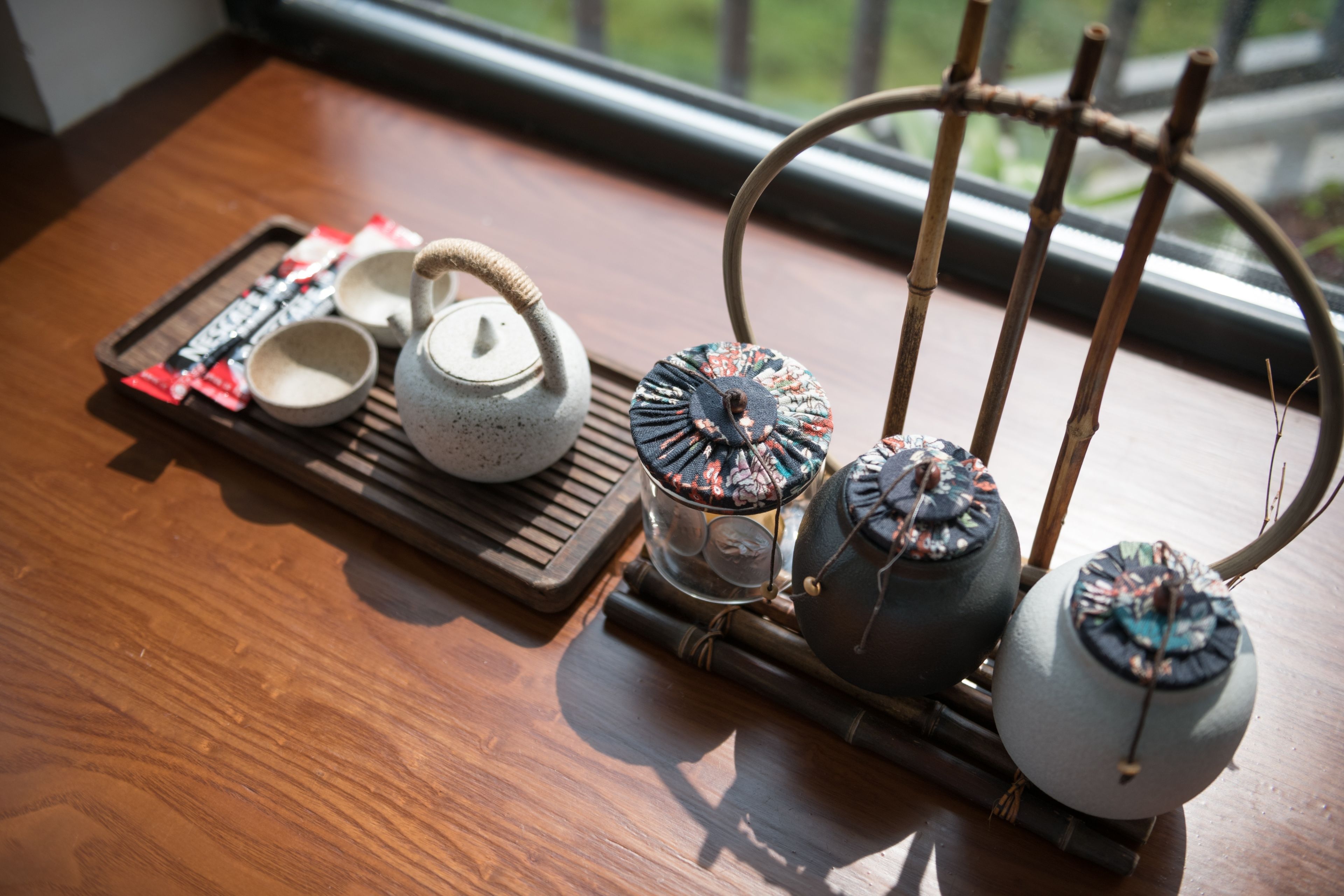 A wooden table with a teapot, cups, and a tray with tea bags.