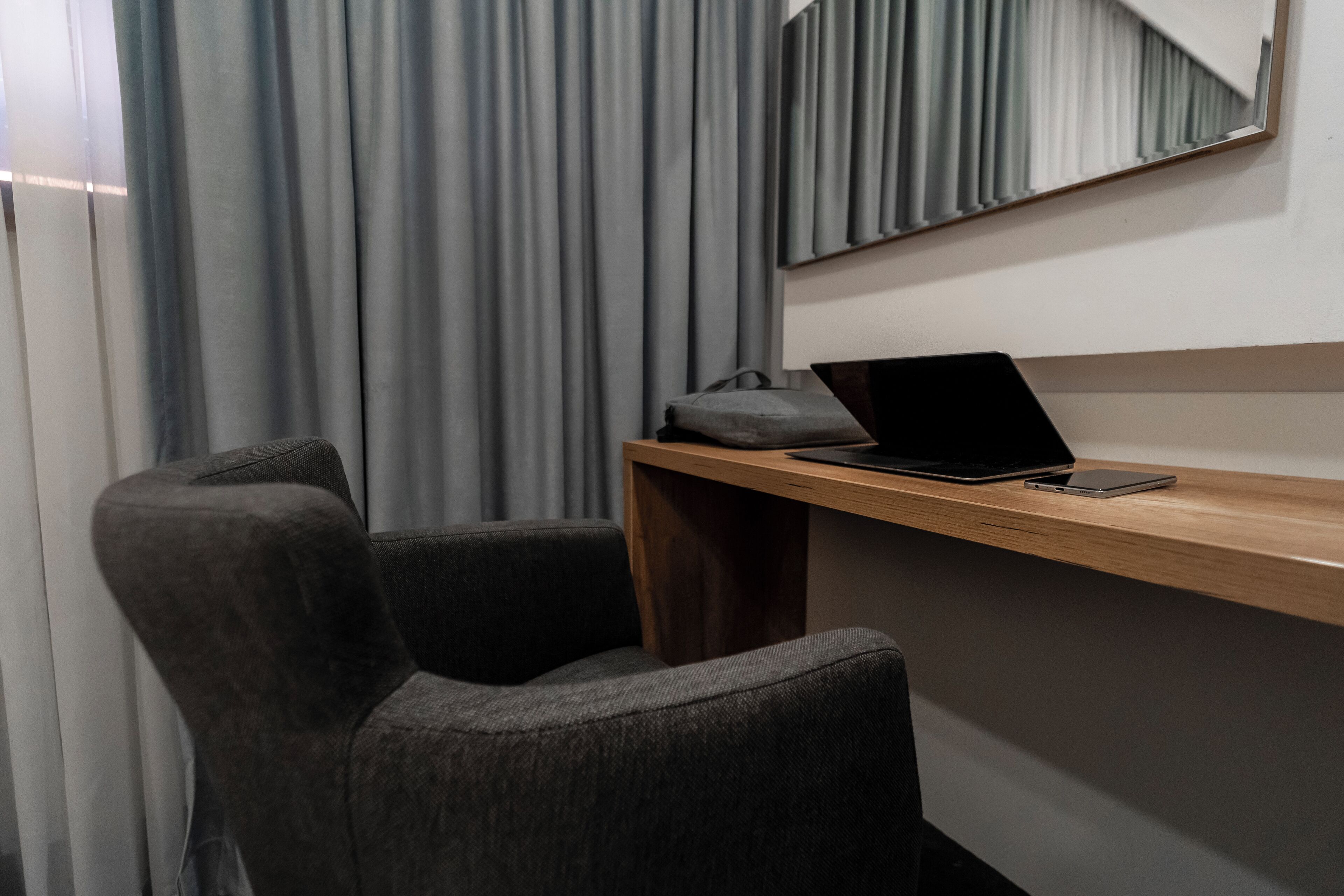 A modern room with a wooden desk, a laptop, and a smartphone.