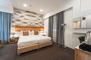 Une chambre d’hôtel moderne dotée d’un grand lit, d’une tête de lit en bois, d’un téléviseur à écran plat et d’un mini-bar.