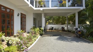 A two-story building with a covered patio area, potted plants, and a motorcycle parked outside. - Araliya Blue Beach View Hotel (Negombo)