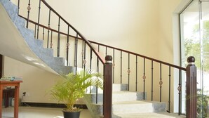 A staircase with a wooden handrail and metal balusters, leading to a landing area with a potted plant and a small table. - Araliya Blue Beach View Hotel (Negombo)