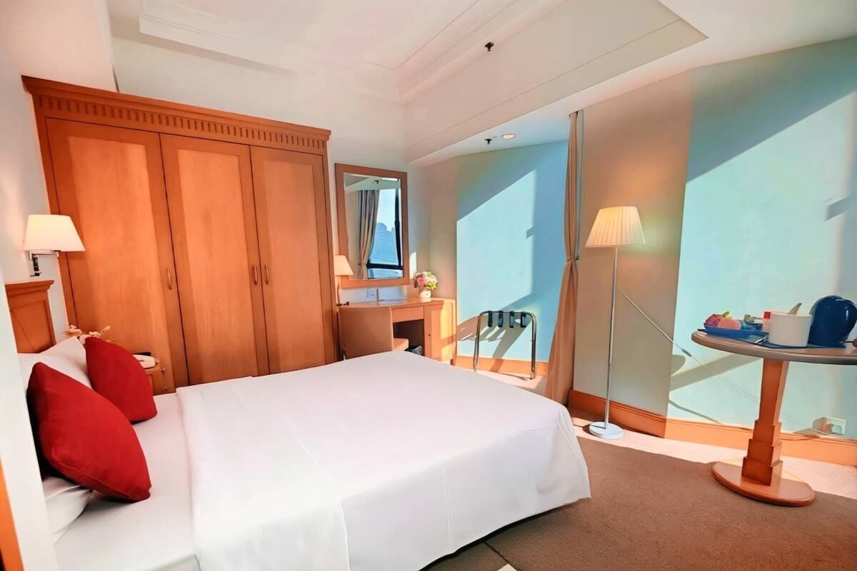 Ein Hotelzimmer mit einem großen Bett, einem Holzschrank, einem Schreibtisch und einem kleinen Tisch mit einer Lampe.