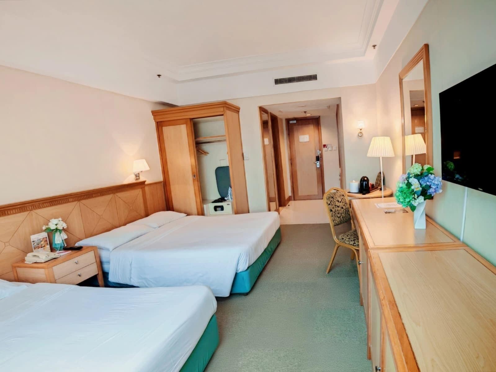 Ein Hotelzimmer mit zwei Betten, einem Schreibtisch, einem Sessel, einem Fernseher und einem durchgegangenen Tür angedeuteten Badezimmer.