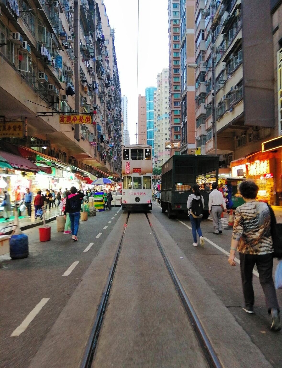 Um eléctrico a percorrer uma rua urbana movimentada, ladeada por edifícios altos.