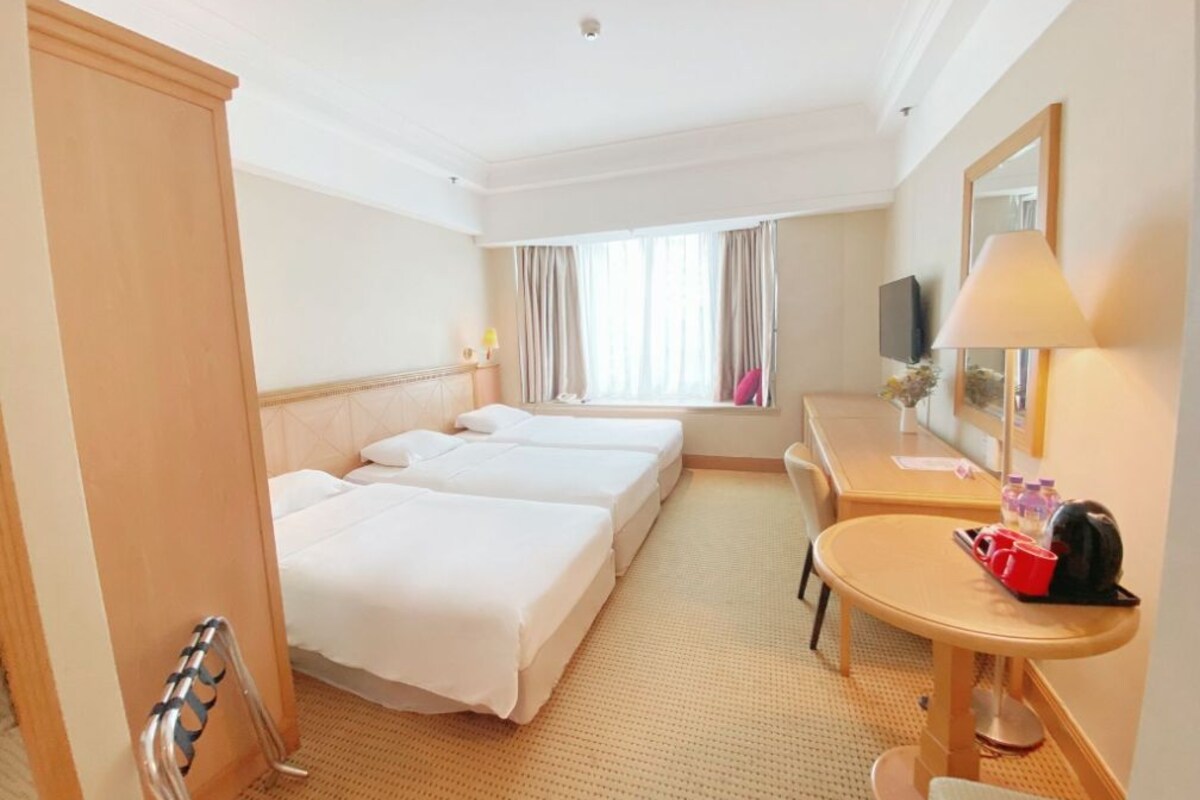 Habitación de hotel con dos camas, un escritorio, una silla, un televisor y una ventana con cortinas.