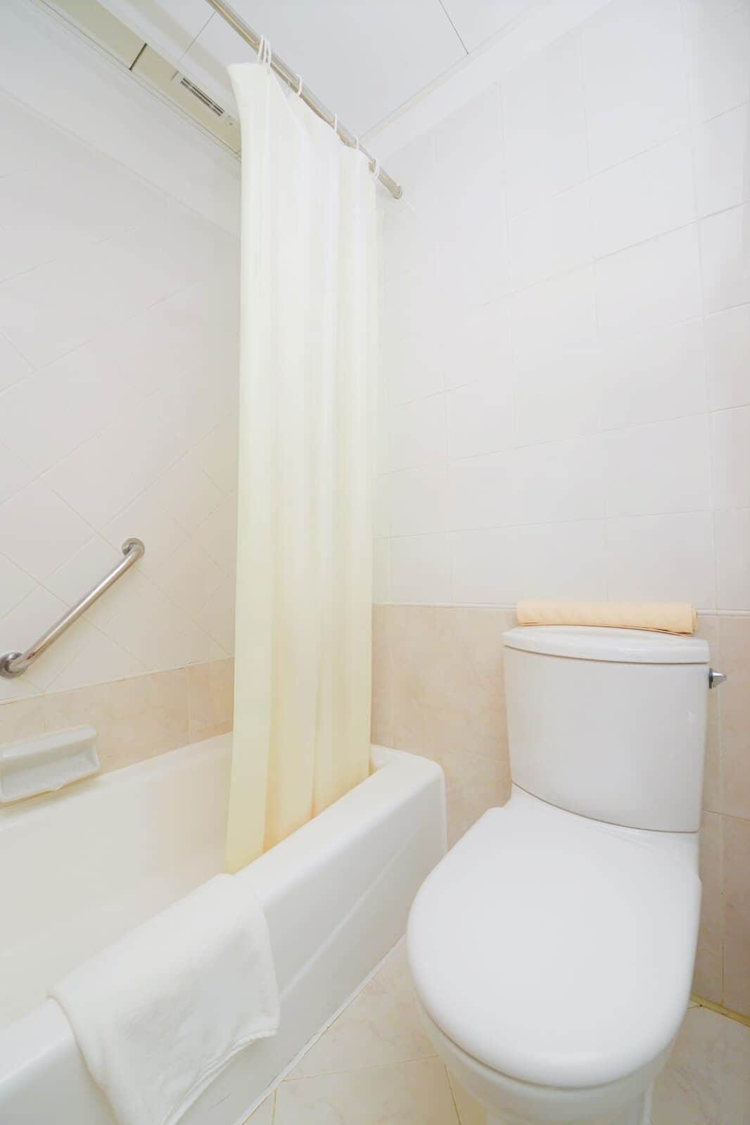 A bathroom with a bathtub, toilet, and shower curtain.