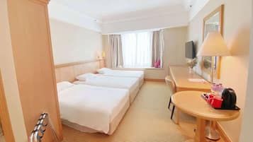 Habitación de hotel con dos camas, un escritorio, una silla, un televisor y una ventana con cortinas.