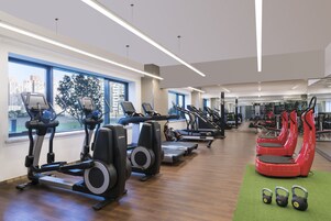 A gym with treadmills, elliptical machines, and red exercise bikes.