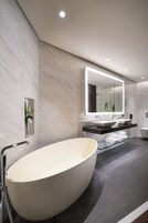 A modern bathroom with a freestanding bathtub, a large mirror, and a vanity with two sinks.