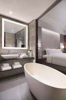 A modern bathroom with a large freestanding bathtub, a large mirror, and a vanity with a sink and towel rack.