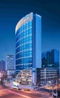 Un hotel moderno con fachada curva, ventanas grandes y el nombre 'AMXRA' en la parte superior.