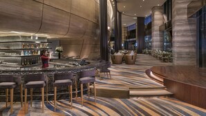 A modern bar area with a curved counter, bar stools, and a variety of bottles.