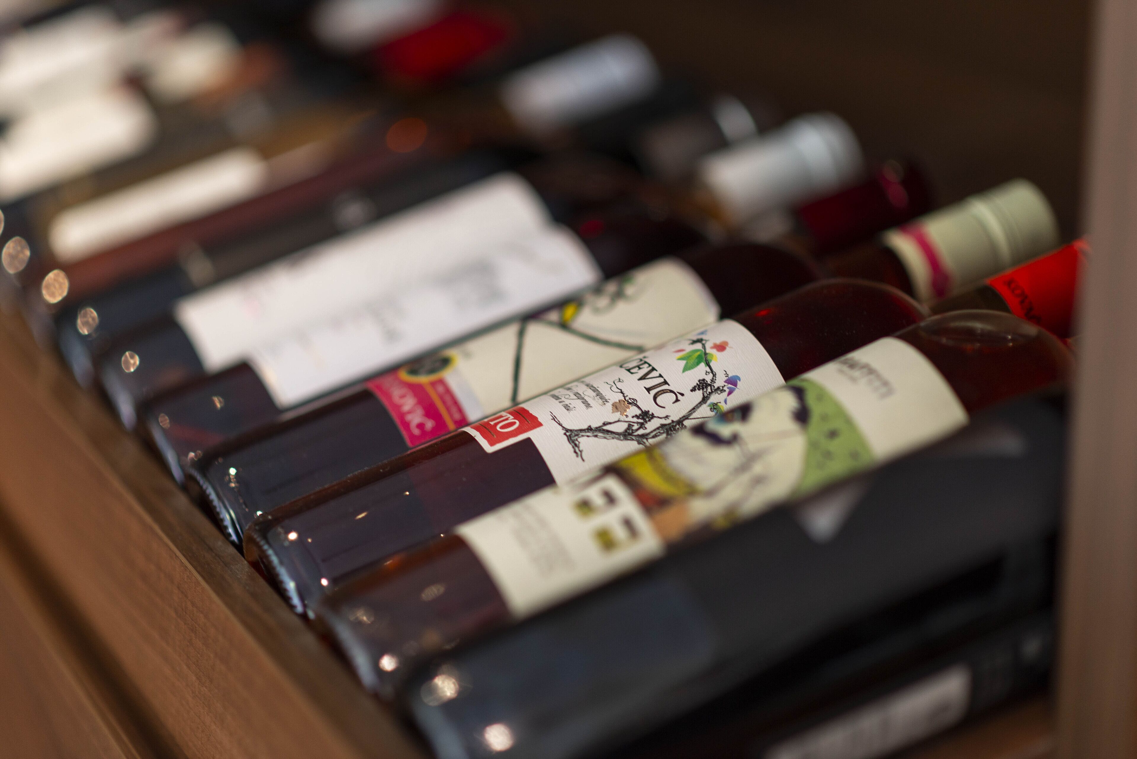 Varias botellas de vino con etiquetas, dispuestas sobre una superficie de madera.