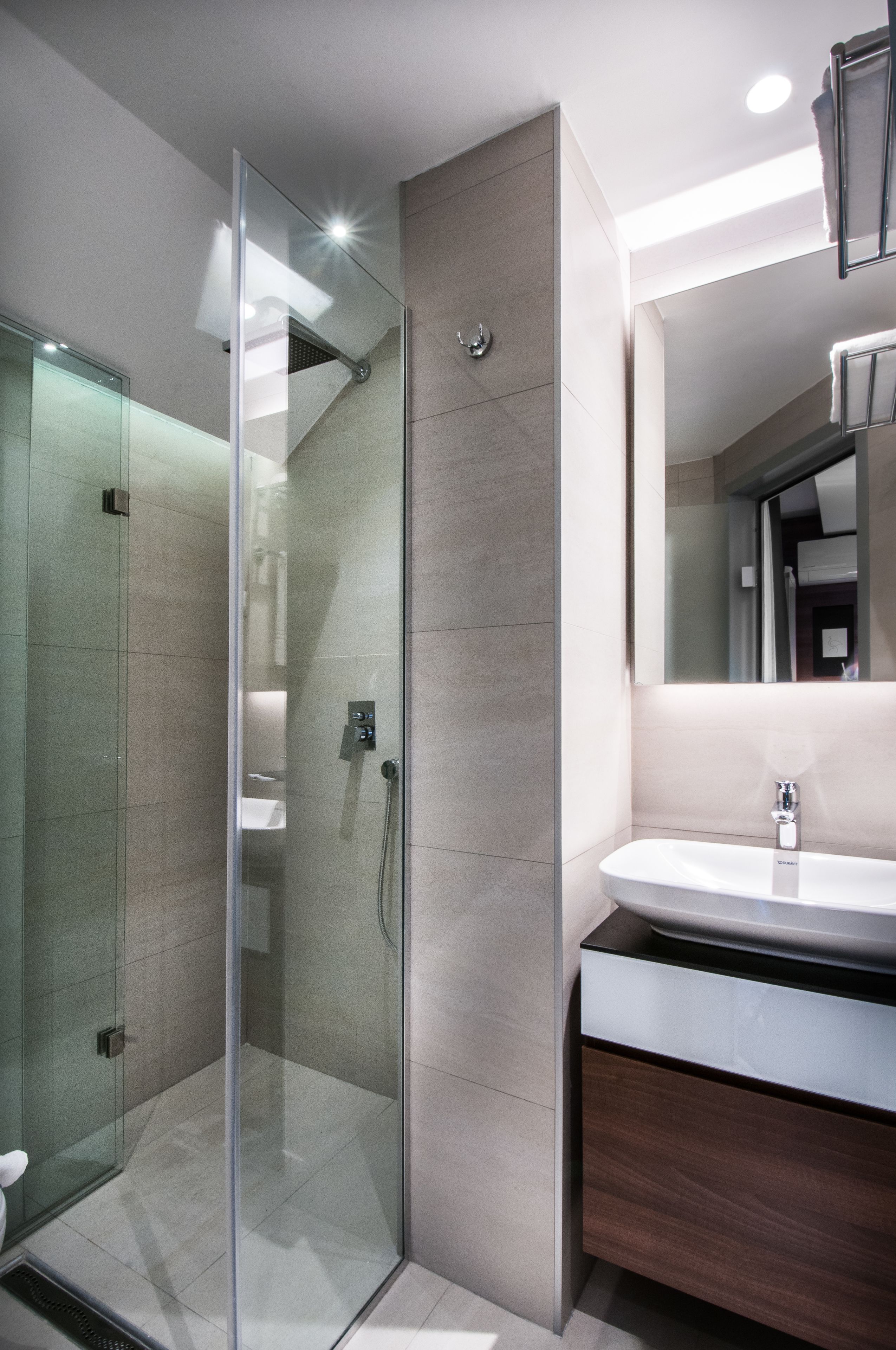 A modern bathroom with a glass-enclosed shower, a vanity with a mirror, and a sink.