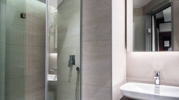A modern bathroom with a glass-enclosed shower, a vanity with a mirror, and a sink.