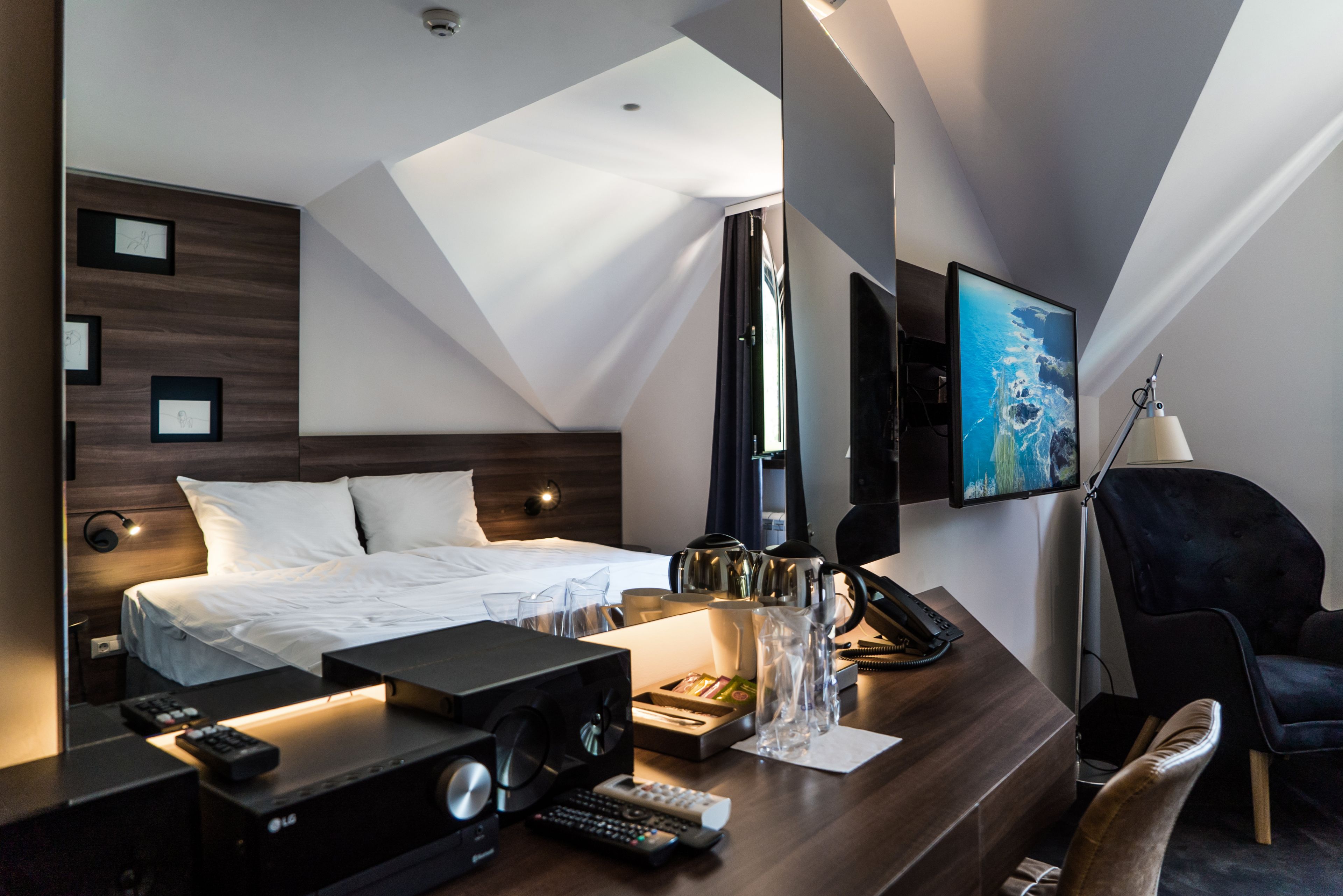 Habitació d'hotel moderna amb llit, escriptori i televisió.
