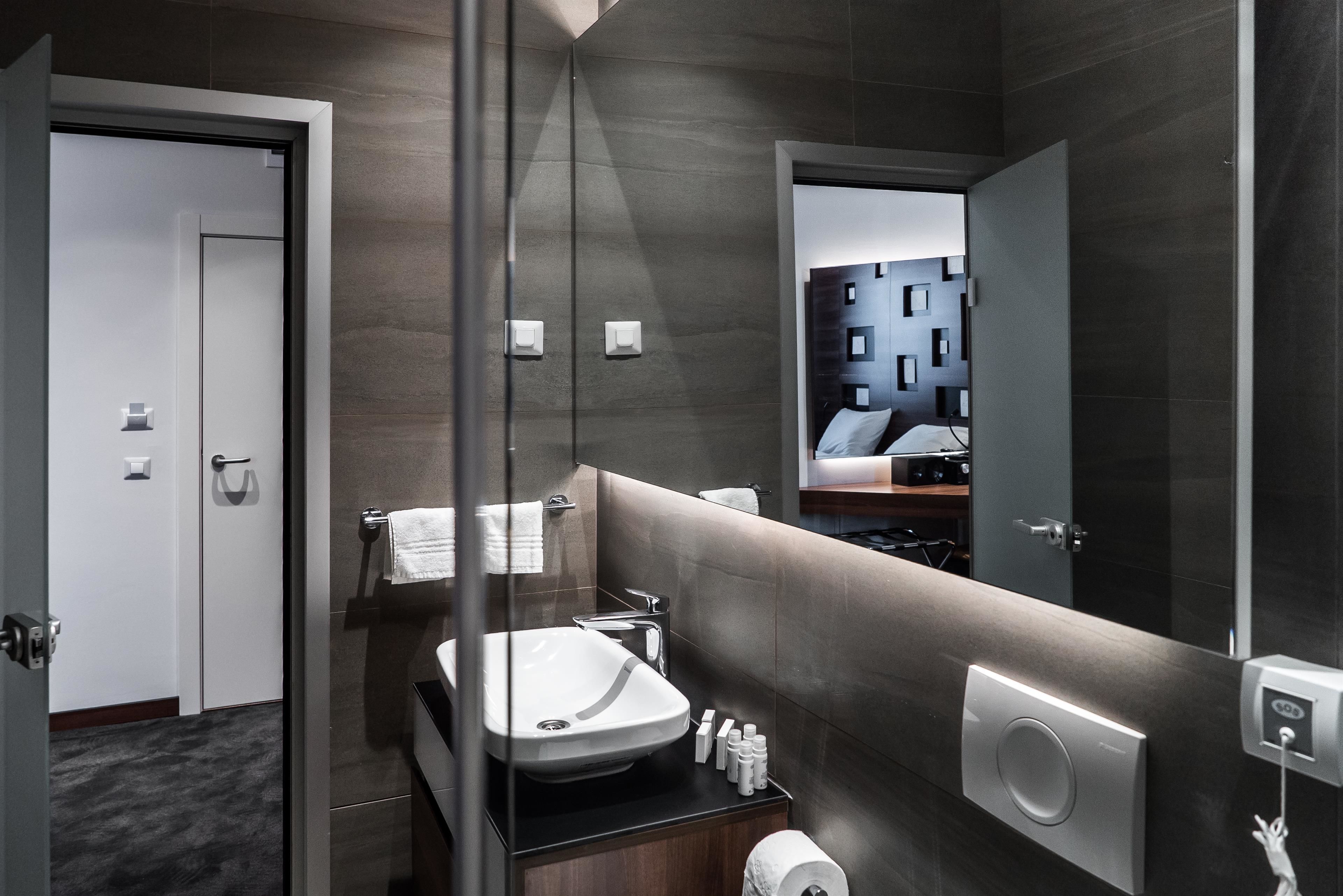 A modern bathroom with a large mirror, a sink, and a toilet.