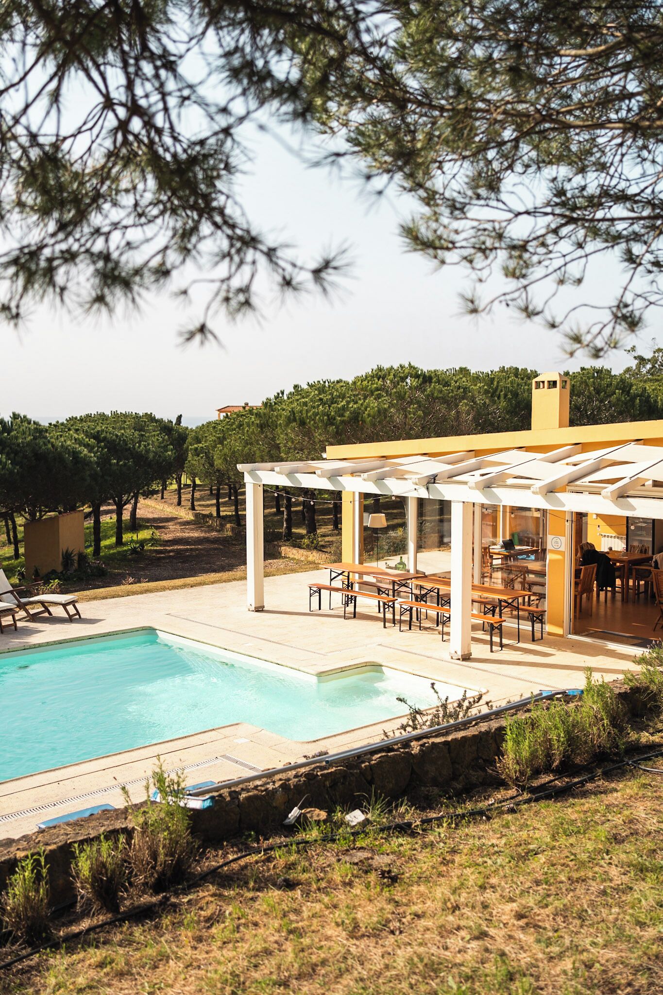 A pool area with a pergola, outdoor seating, and a view of the surrounding landscape.