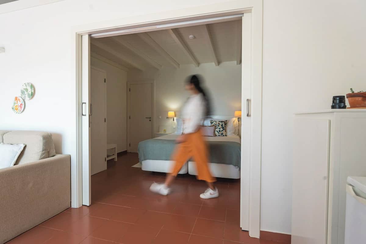 A modern hotel room with a bed, bedside lamps, and a sofa.