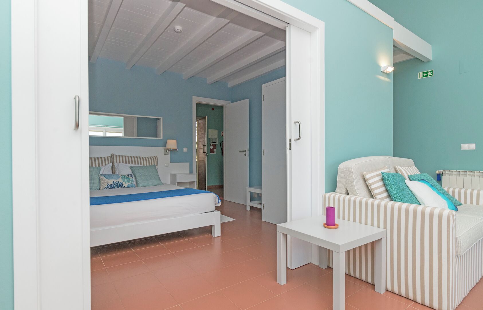 Un dormitorio con una cama, una mesita de noche, una silla y una pequeña mesa.