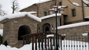 Een gebouw van steen met een besneeuwde ingang en een metalen poort.