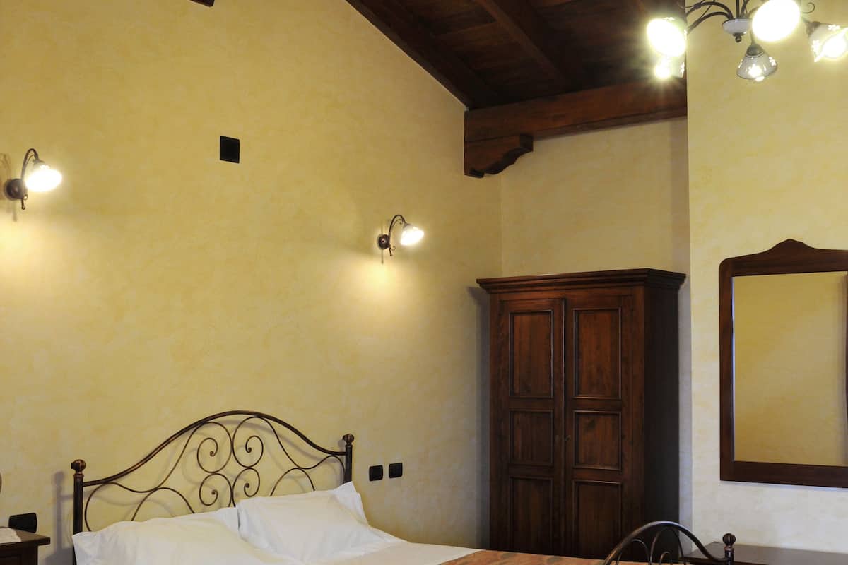 Een slaapkamer met een bed, een houten garderobe en een spiegel aan de muur.