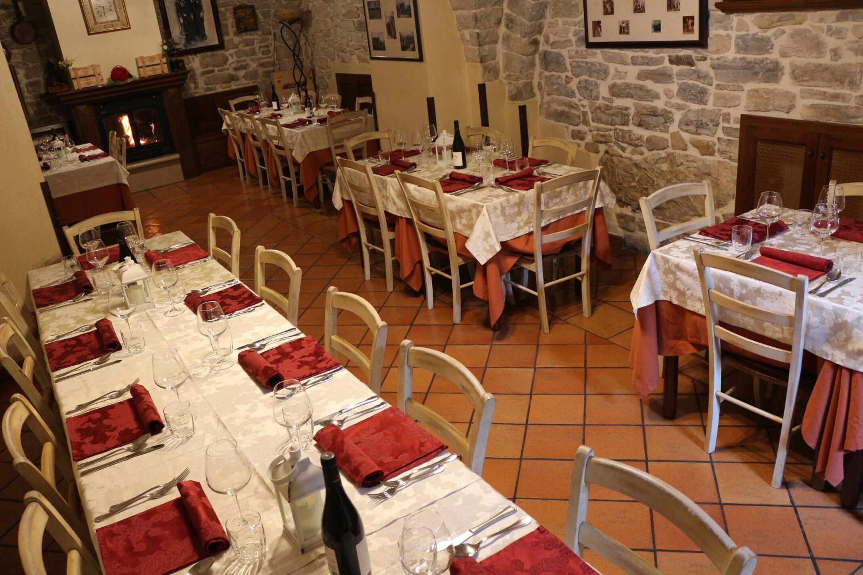 A dining area with multiple tables set for meals, stone walls, and a fireplace.