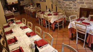 A dining area with multiple tables set for meals, stone walls, and a fireplace.