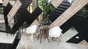 Um interior moderno com um chão de azulejos geométricos em preto e branco, cadeiras brancas e um sofá de couro preto.