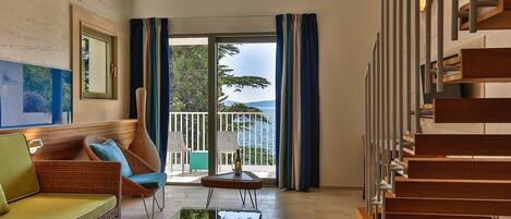 Un intérieur moderne avec un canapé, une table en verre, un escalier et un balcon offrant une vue dégagée.