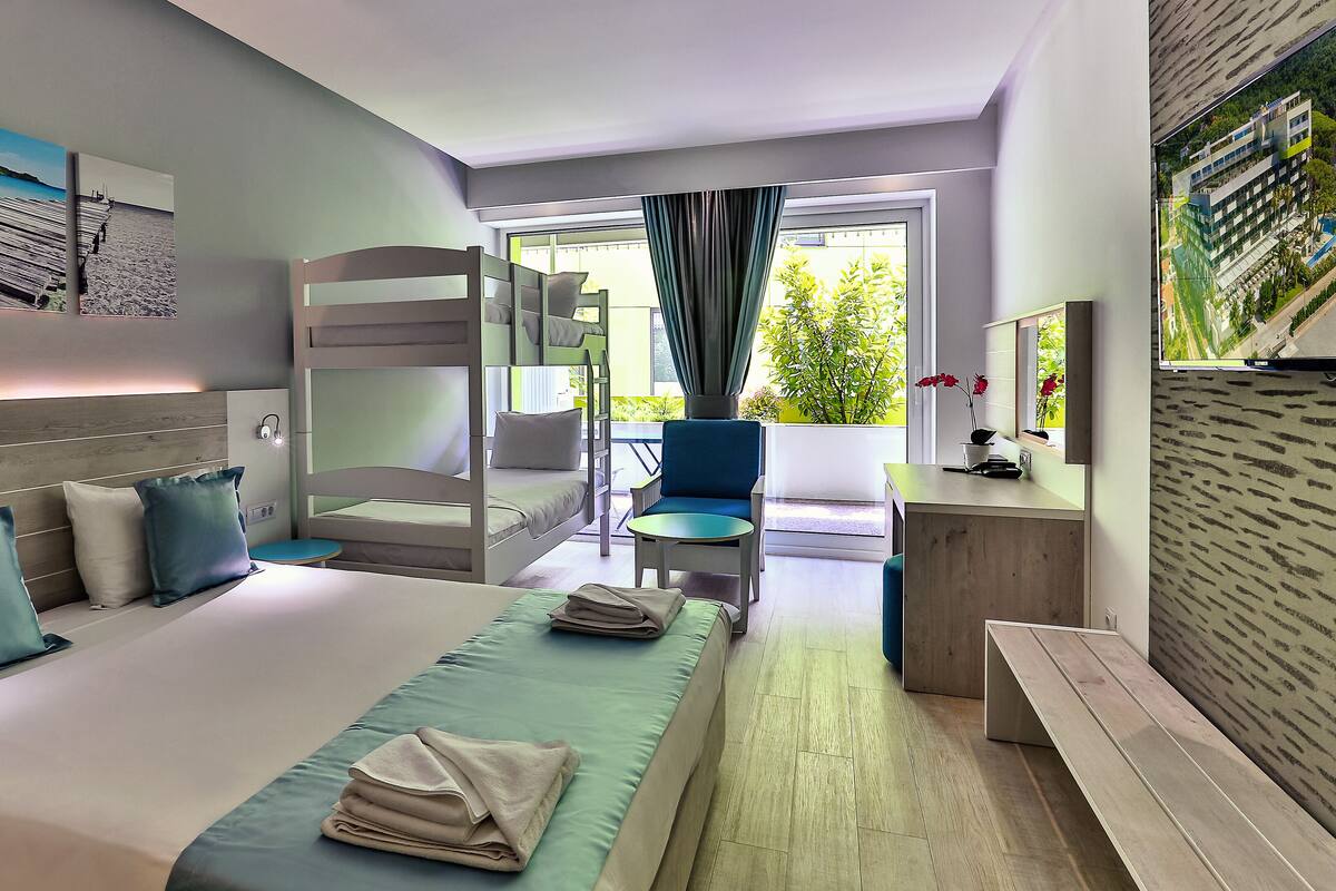 Habitación de hotel con literas, escritorio, silla y vistas al exterior.