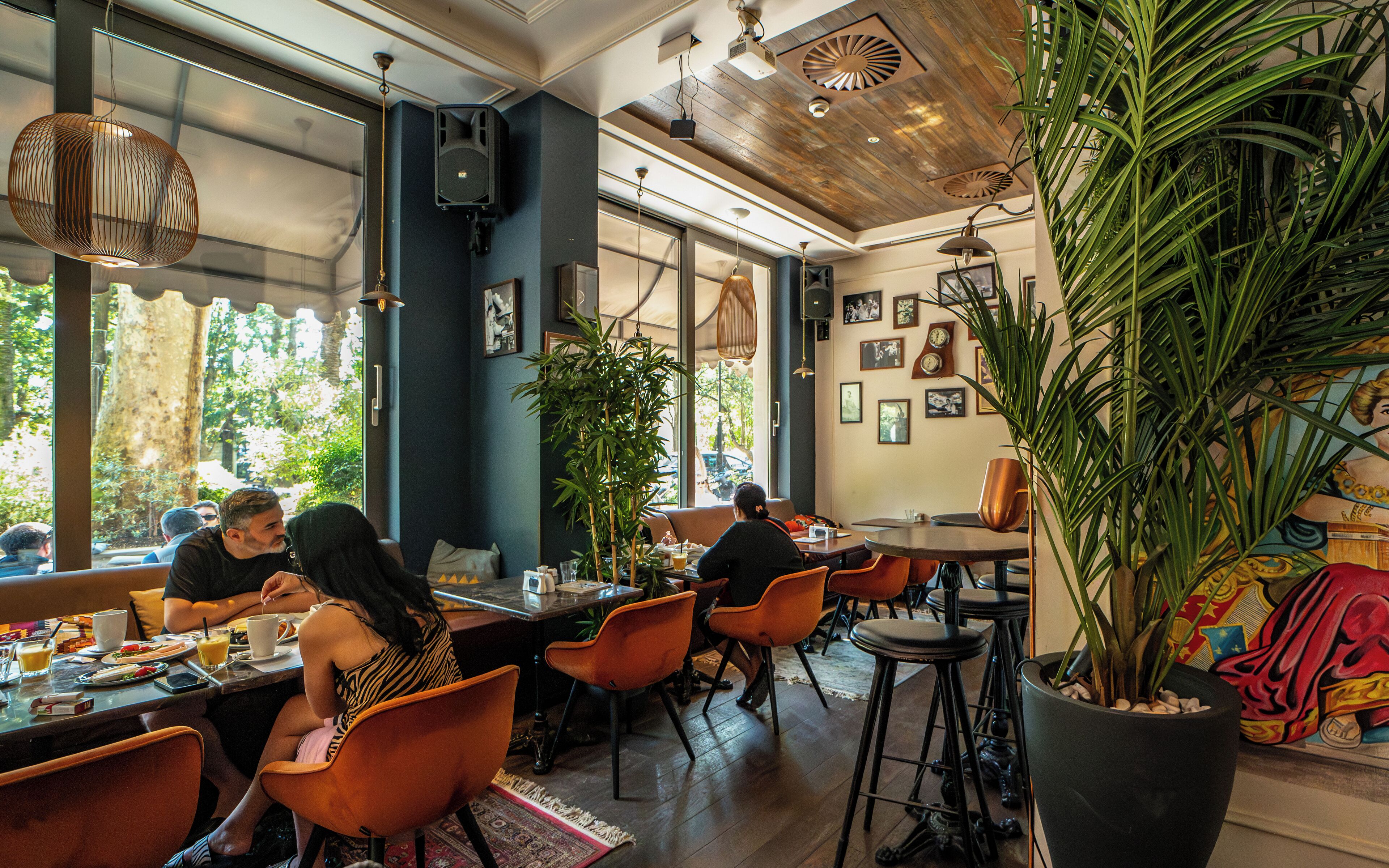 Un restaurante con techo de madera, ventanas amplias y plantas de interior.