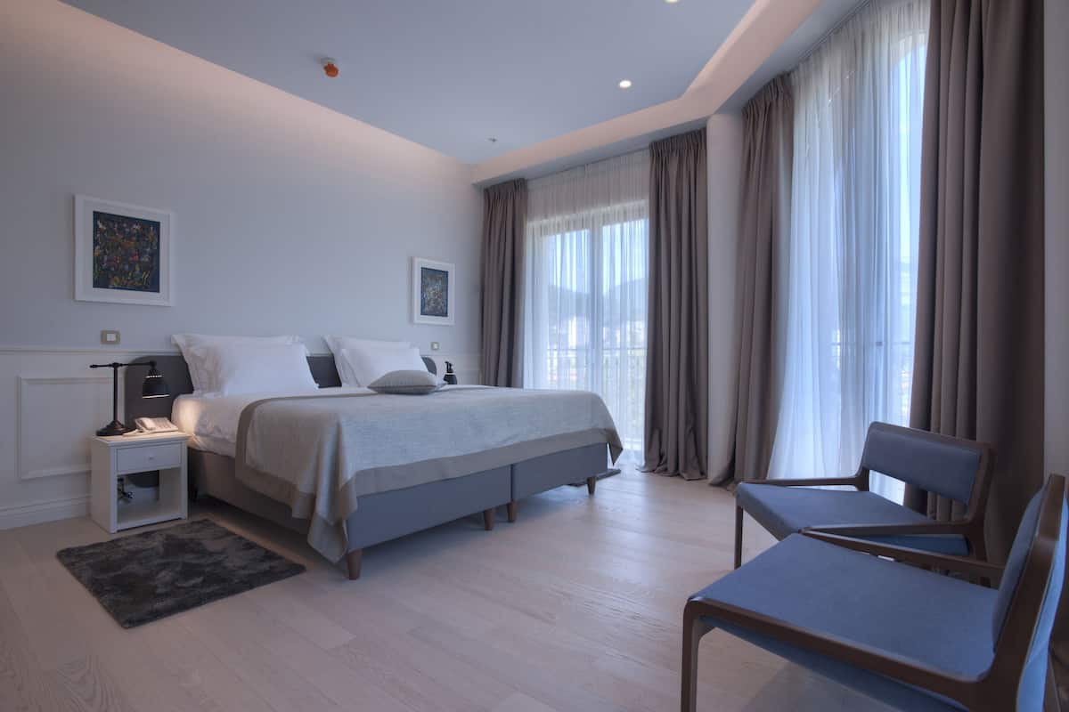 A modern bedroom with a large bed, bedside tables, a desk, and a chair.