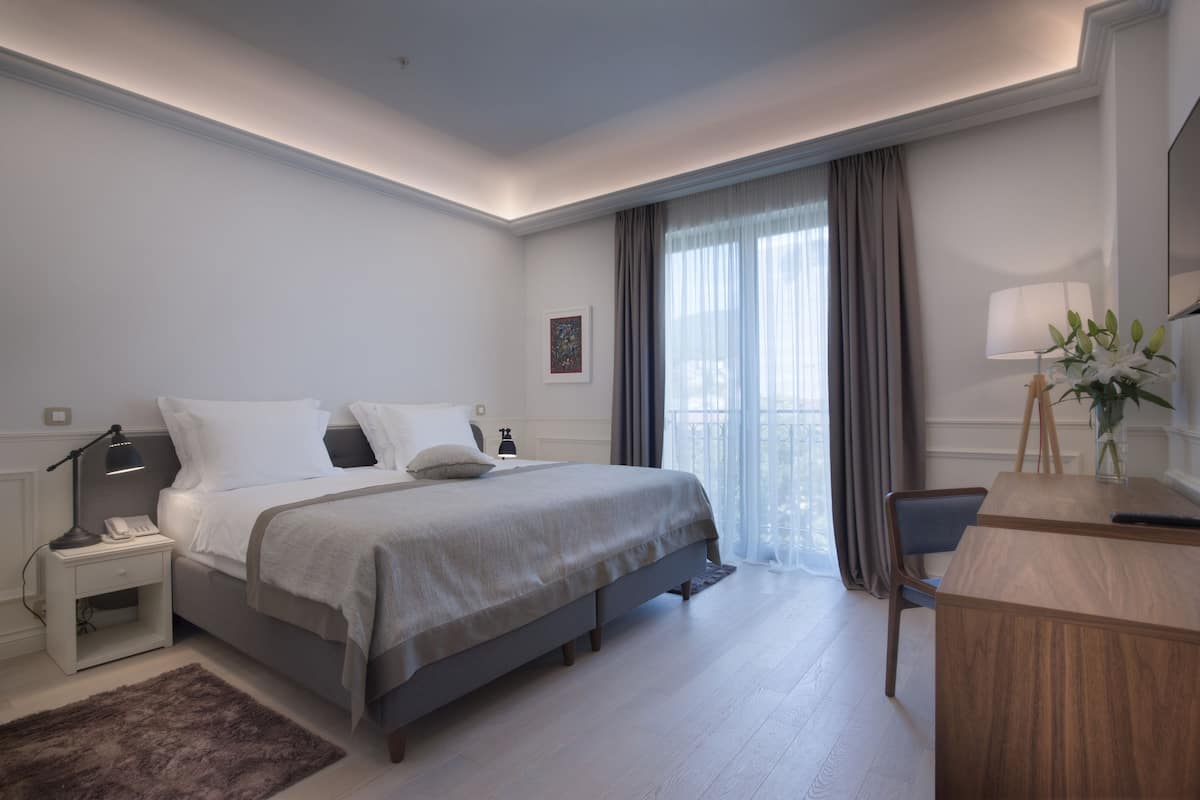 A modern bedroom with a bed, bedside table, lamp, and a desk with a chair.