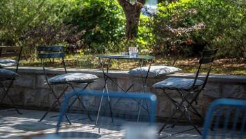 A patio with a table and chairs, surrounded by a stone wall and greenery.