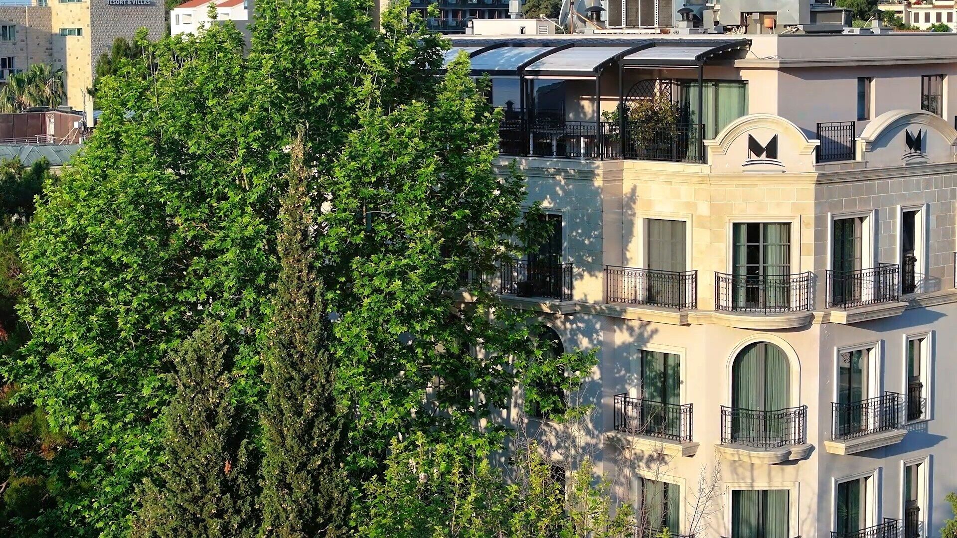 Un edificio de varios pisos con balcones, ventanas amplias y un llamativo logo 'M' en la fachada.