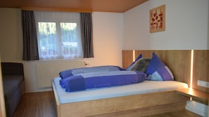 Un dormitorio con una cama de madera, una ventana con cortinas, un radiador y una obra de arte colgada en la pared.